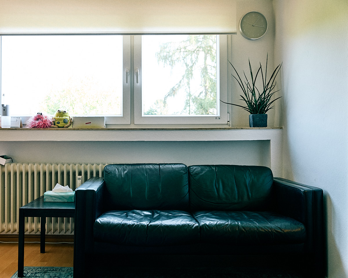 Schwarzes Ledersofa vor großem Fenster mit Blick ins Grüne im 3. OG