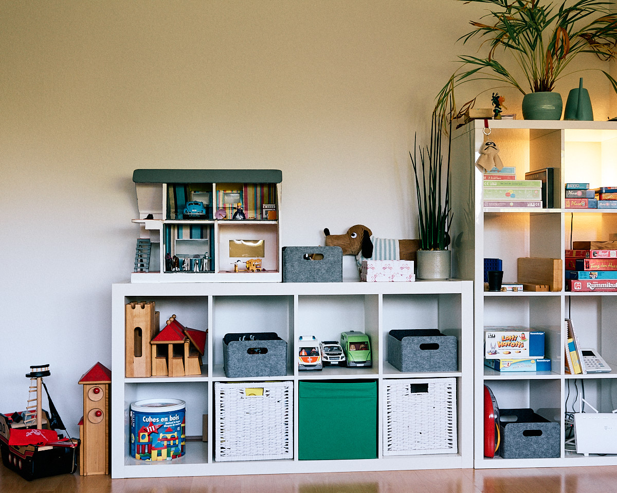 Gesamtansicht des Regals mit Spielen, Puppenhaus, Lampen und Pflanze