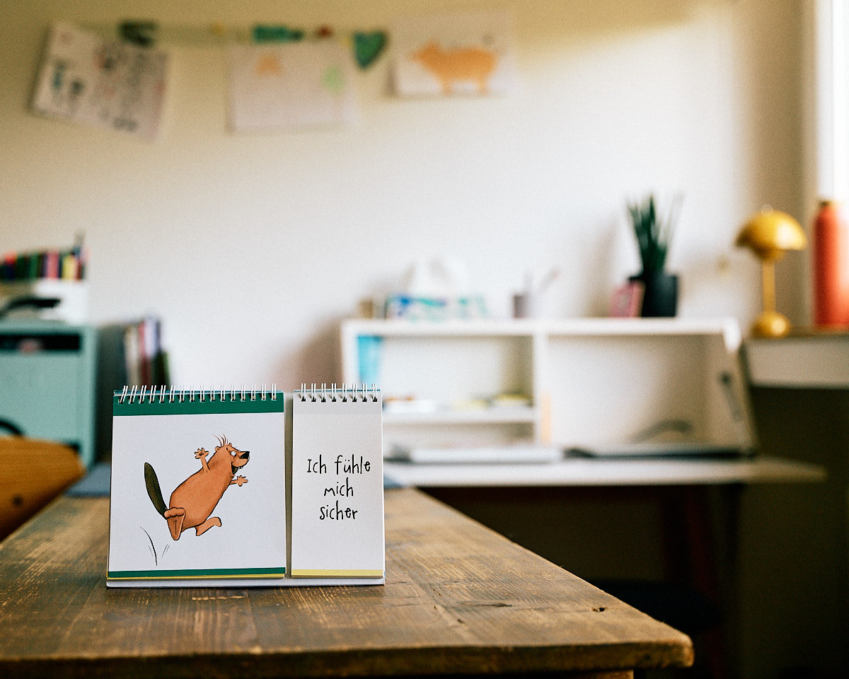 Langer Arbeitstisch, an der Wand unscharfe Kinderzeichnungen